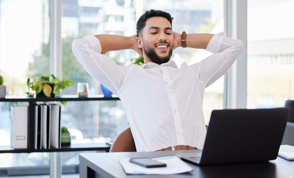 Laptop, relax and happy business man stretching at a desk after deadline, project and review satisfaction in office. Smile, stretch and Mexican male manager relieved with online development or result