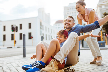 Young family having fun with a skateboard downtown in the city