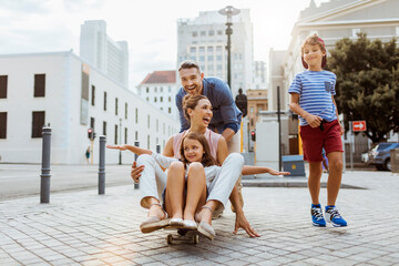 Young family having fun with a skateboard downtown