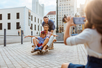 Young family taking a picture downtown while skateboarding together