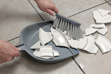 dustpan and brush used to clean a broken plate from the kitchen floor. - obrazy, fototapety, plakaty