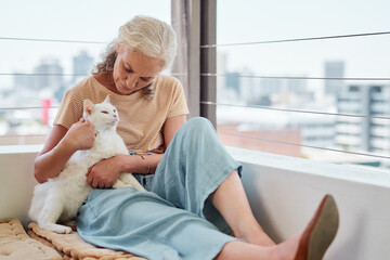 Cuddles keep the heart content. Shot of a mature woman spending quality time with her cat on the balcony at home.