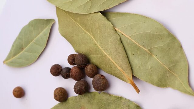  Dried green bay leaf and black allspice peas pepper, rotation in circle. spice for dumplings and soup Macro. vertical video.