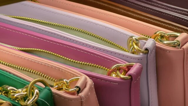 Women's leather zipper handbags in different colors in the accessories store window. Close up