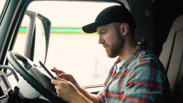 Truck drivers hand holding tablet checking the product list. Driver writing electronic log books. Right hand drive car