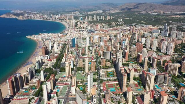 Aerial drone footage of the beautiful city of Benidorm in Spain in the summer time showing the Playa de Levante beach and the high rise apartments and hotels in the city in the summer time