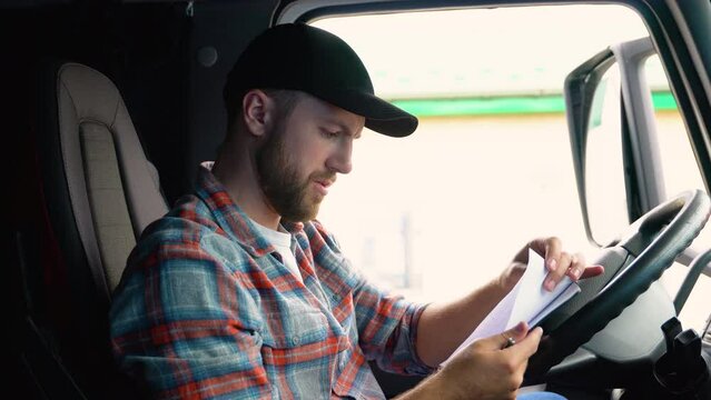 Delivery man with cardboard box checking list in truck. Courier checking list on clipboard. Deliveryman sitting in truck and checking the delivery list