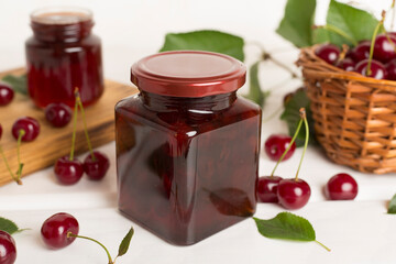 Jar with tasty homemade cherry jam on wooden table