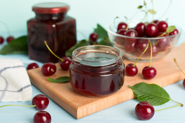Jar with tasty homemade cherry jam on wooden table