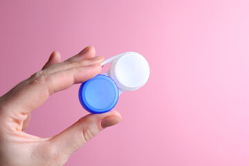 Contact lens container in hand on a colored background. Vision correction. 