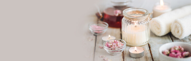 Concept of natural organic flower, herbal ingredients for spa treatment for relaxation and detox. Hot tea with rose extract, petals for beauty procedures, towel, candles. Detention, meditation banner