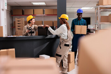 Smiling storehouse operators chatting at reception desk doing inventory. Post office storage...