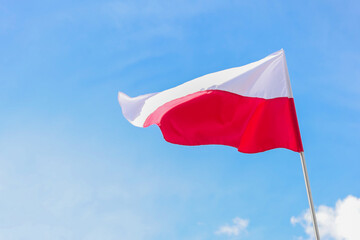 The national flag of Poland in the daytime on the background of the blue sky