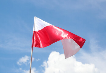 The national flag of Poland in the daytime on the background of the blue sky