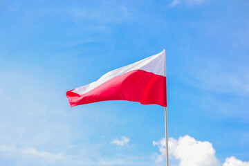 The national flag of Poland in the daytime on the background of the blue sky