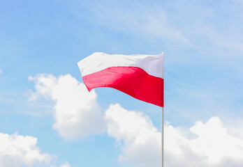 Fototapeta na wymiar The national flag of Poland in the daytime on the background of the blue sky