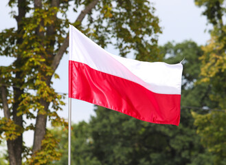 The national flag of Poland in the daytime on the background of the blue sky
