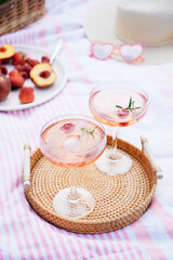 Pink drinks, cocktail with ice, raspberry, rosemary. Two glasses with martini, champagne, cider, lemonade on the blanket with fruit plate, picnic basket, Cozy summer picnic on nature. Selective focus