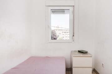 A spartan bedroom with dirty white walls