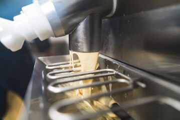 Closeup indoor shot of pasteurizer machine pouring ice cream into steel freezer. Ice cream manufacture concept. High quality photo