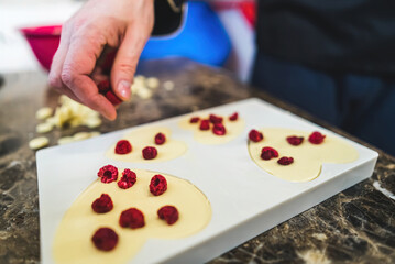 Valentine's Day gift concept. Hand of chef crefully placing raspberries on white chocolate chunks...