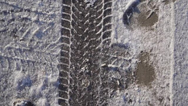 Tire tracks on a thin layer of snow in winter.