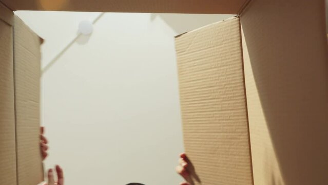 happiness asian marry couple enjoy exiting while unpack stuff moving to new home house relocation renovation  joyful couple surpring hand open cardboard unpack view from inside the box home moving 