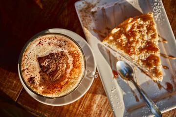Top view of a cup of coffee and a slice of apple pie on a wooden table