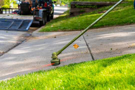 Landscaping Company Tending to A Front Lawn and Flower Bed Cutting Grass and Blowing Debris