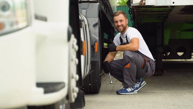 Portrait of professional truck mechanic in car repair service. Mechanic changes the truck tire