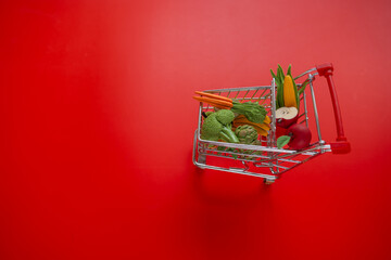grocery consumer basket.Shopping cart with groceries on a red background.Vegetables and fruits...