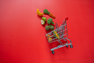 grocery consumer basket.food cost.Rising food prices.Shopping cart with groceries on a red background.Vegetables and fruits price increase.food crisis.Decorative vegetables and fruits.Decorative