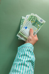  euro money.Hands in a striped shirt holding euro money on a green background.European Union...