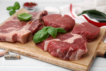 Cut fresh beef meat and basil leaves on white table, closeup