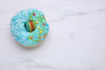 Sweet glazed donut decorated with sprinkles on white marble table, top view and space for text....