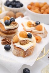 Tasty sandwiches with brie cheese, fresh berries and walnuts on white table, closeup