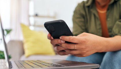 Hands of woman on sofa with phone, laptop and typing for remote work, research and documents for online job. Internet, networking and home office, freelancer on couch with cellphone and computer.