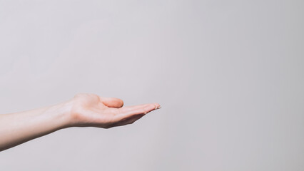 Offering gesture. Open palm. Woman holding copyspace in open hand proposing product isolated on gray empty space background.