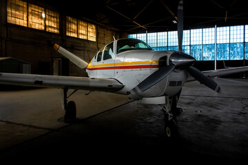 Moody and dramatic aircraft in hanger. Single engine airplane rest in storage. Three blade...