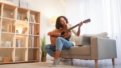 Song learning. Guitar playing. Music hobby. Focused woman musician practicing chords of string...