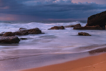 Sunrise seascape with low clouds and waves