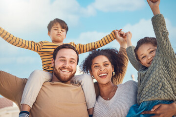 Portrait, motivation and piggyback with a family cheering together against a blue sky. Diversity, love or smile with happy parents and children in the garden of their home for trust or support