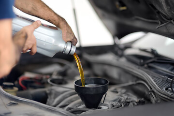 Man auto mechanic repairs car in autoservice, station. Changes oil.