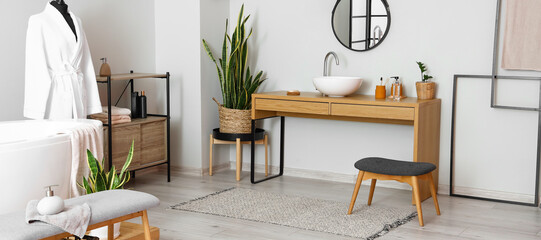 Interior of light bathroom with sink, mirror and table