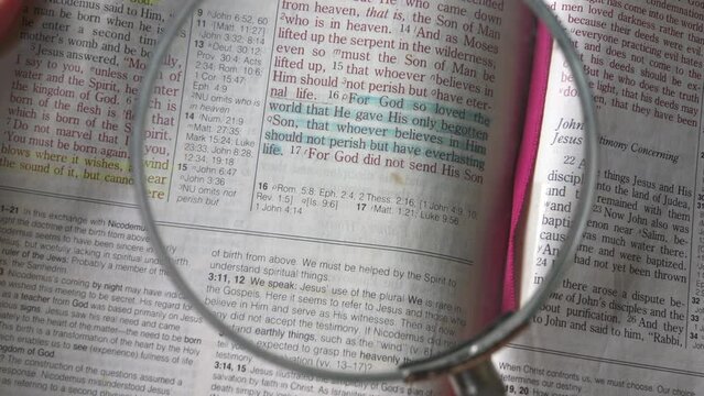 Using a magnifying glass to zoom into the passage of John 3:16 of the new testament in the bible. Highlighted in blue, close up view.