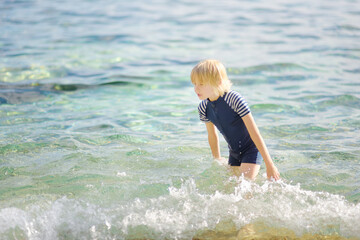 Cute preteen boy is bathing in a sea. Fun beach holiday for children. Summer vacation for kids.