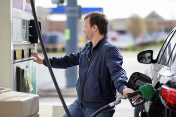Man filling gasoline fuel in car holding nozzle