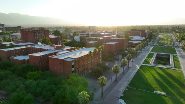 Cinematic aerial establishing shot of academic buildings on college campus of University of Arizona. Beautiful sunrise over Tucson, Arizona school landscape.