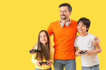Obraz premium Father with his little children playing video game on yellow background