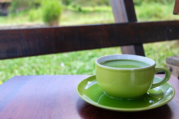 a cup of milk green tea on the table beside lake. the addition of milk to green tea may help...